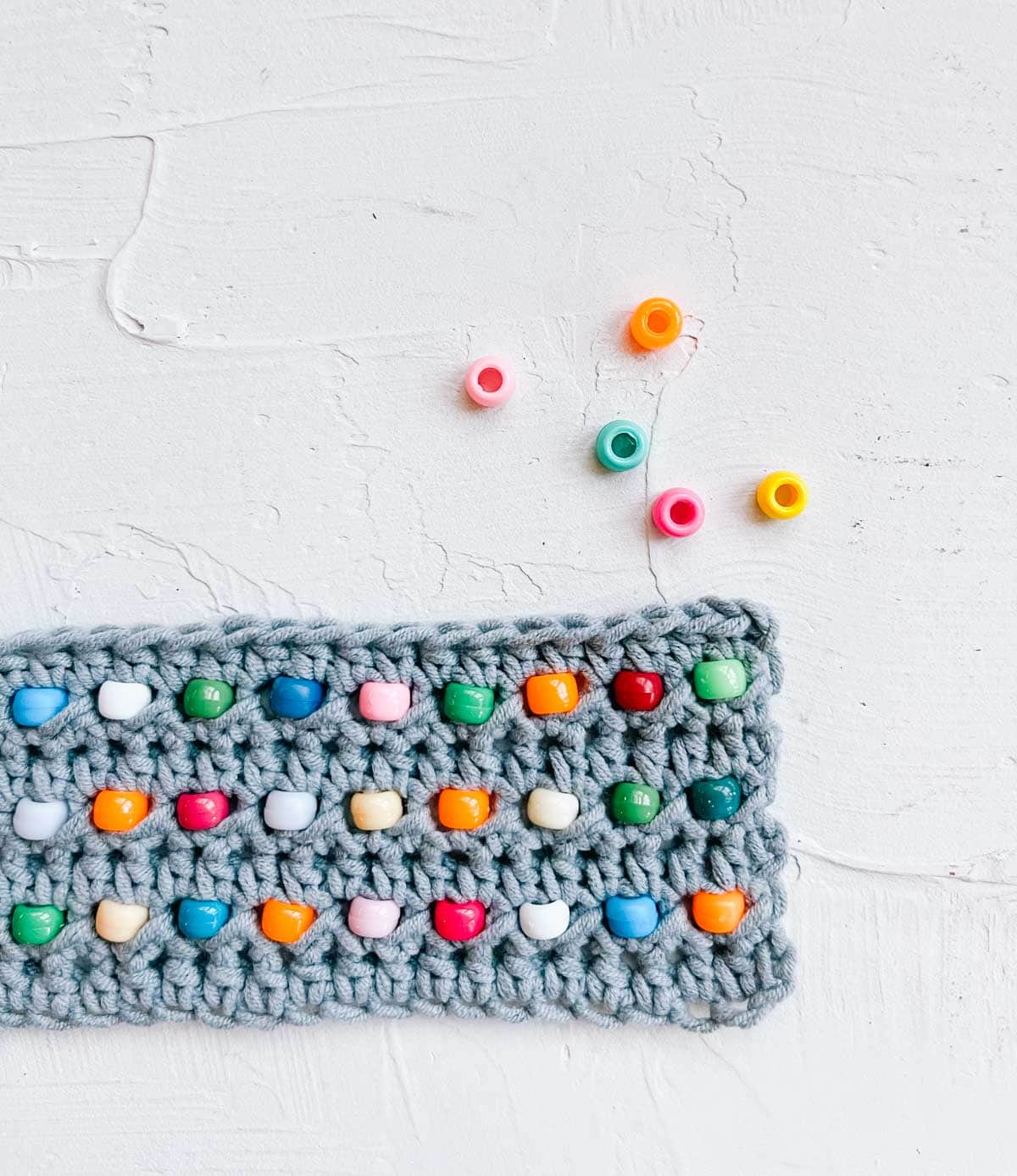 Grey crochet swatch with colorful plastic beads.