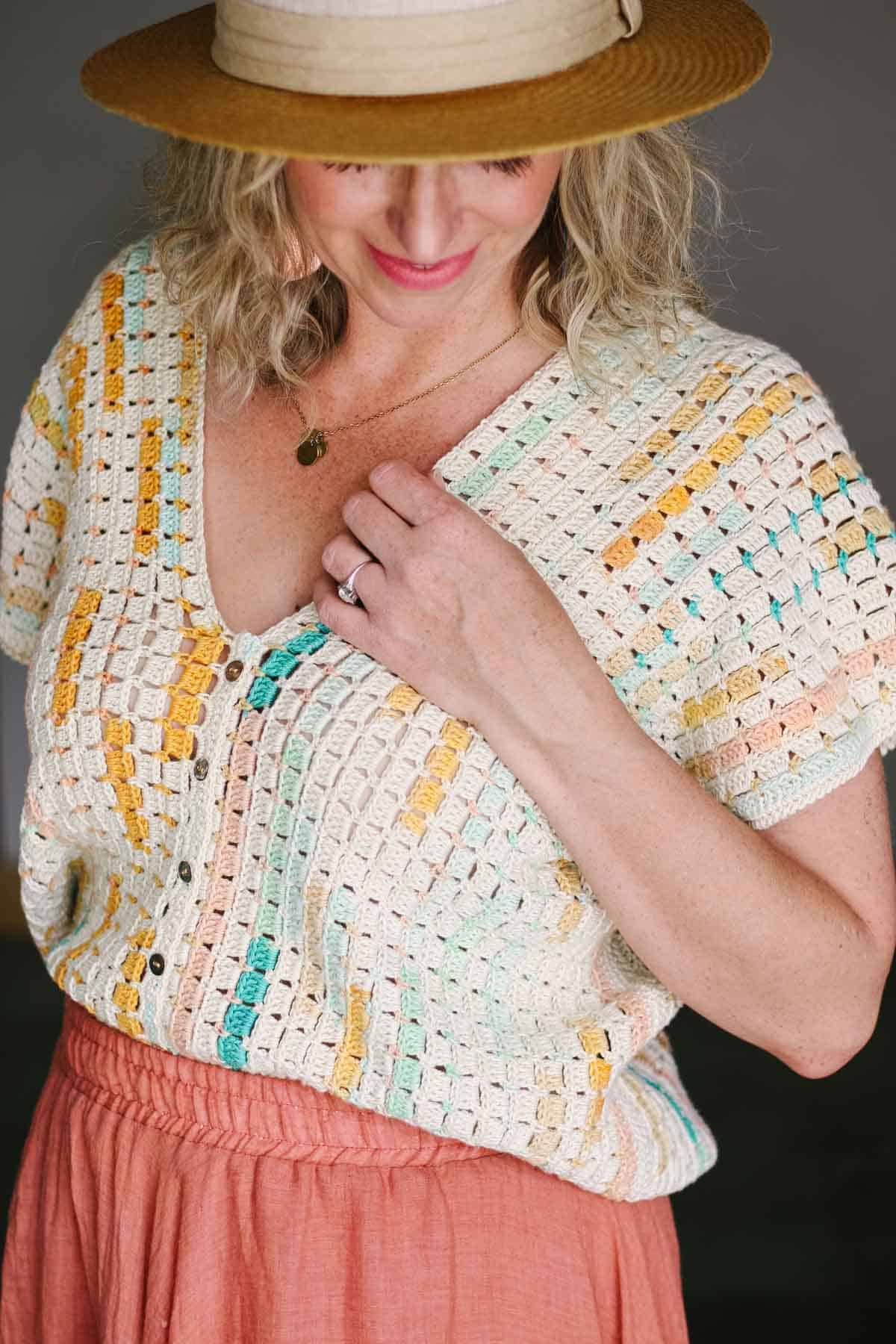 Short sleeve crochet top with buttons on a woman looking downward.