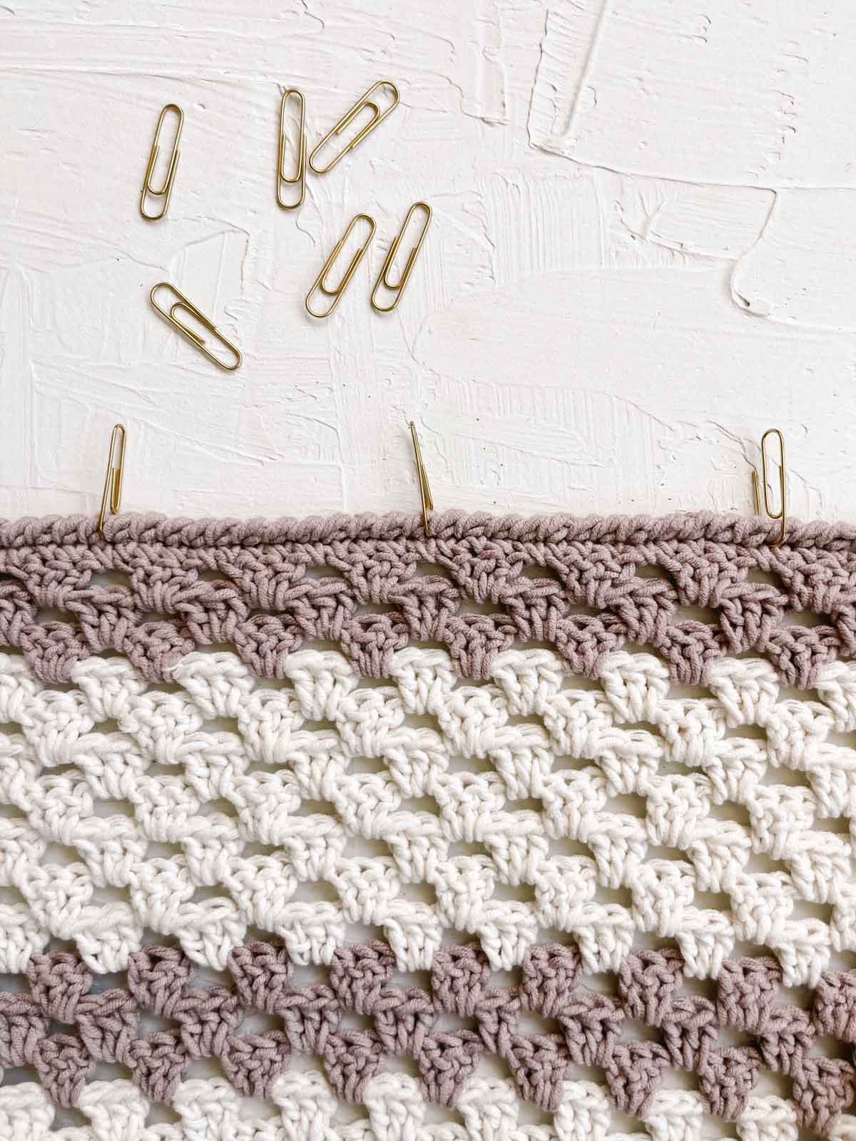 Gold paper clips used as stitch markers in a crochet sweater.