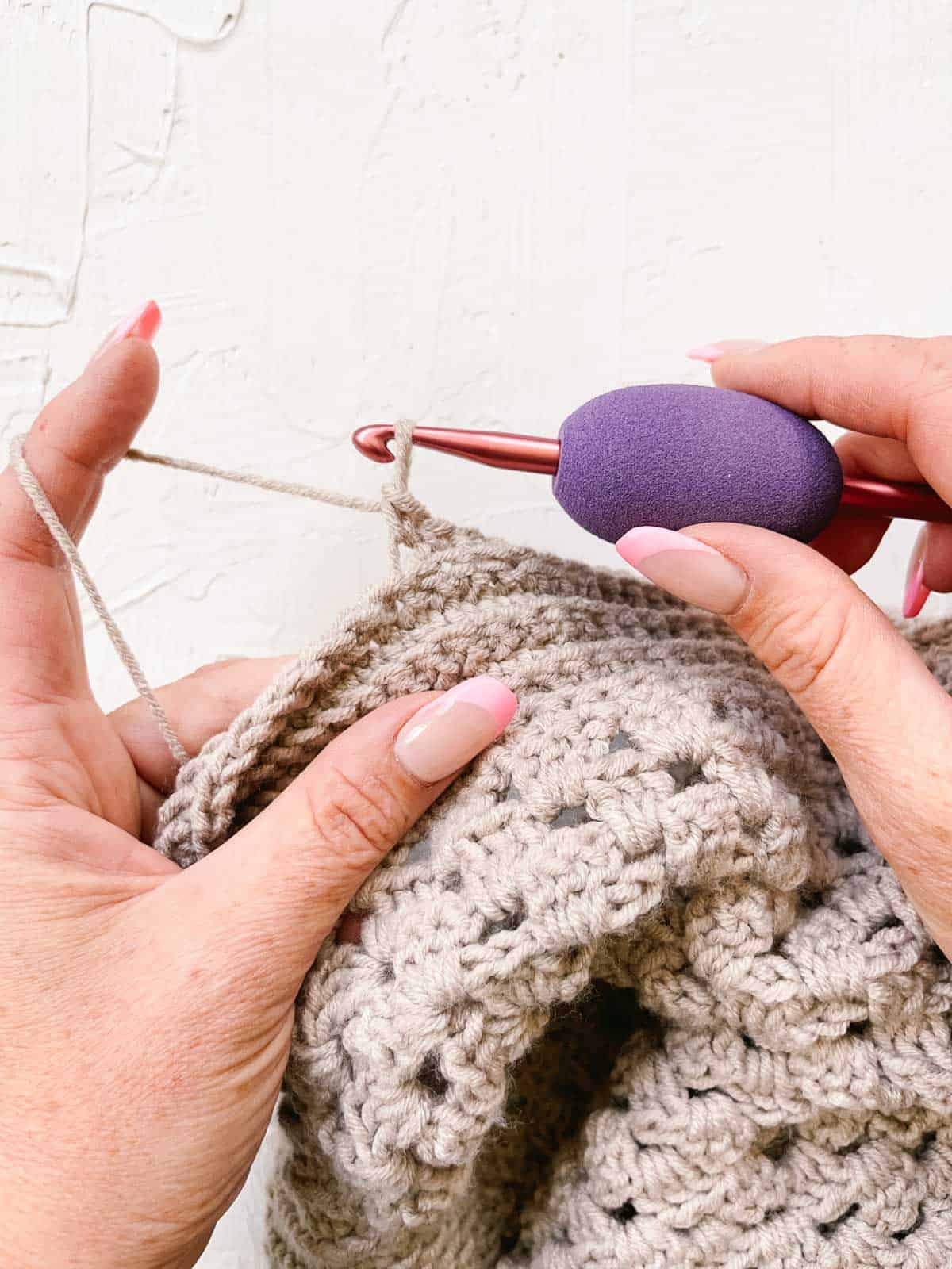 Crocheter using a makeup beauty blender to create an ergonomic handle. 