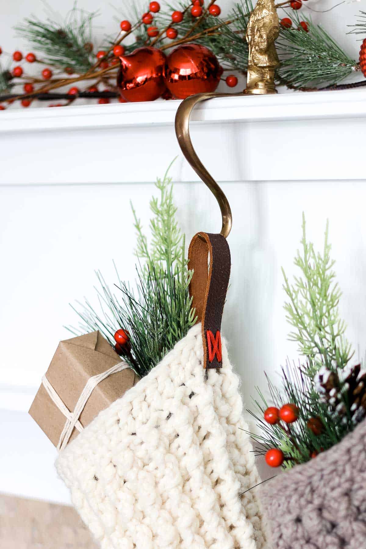 Two Christmas stockings filled with gifts hung by the fireplace with a leather strap.