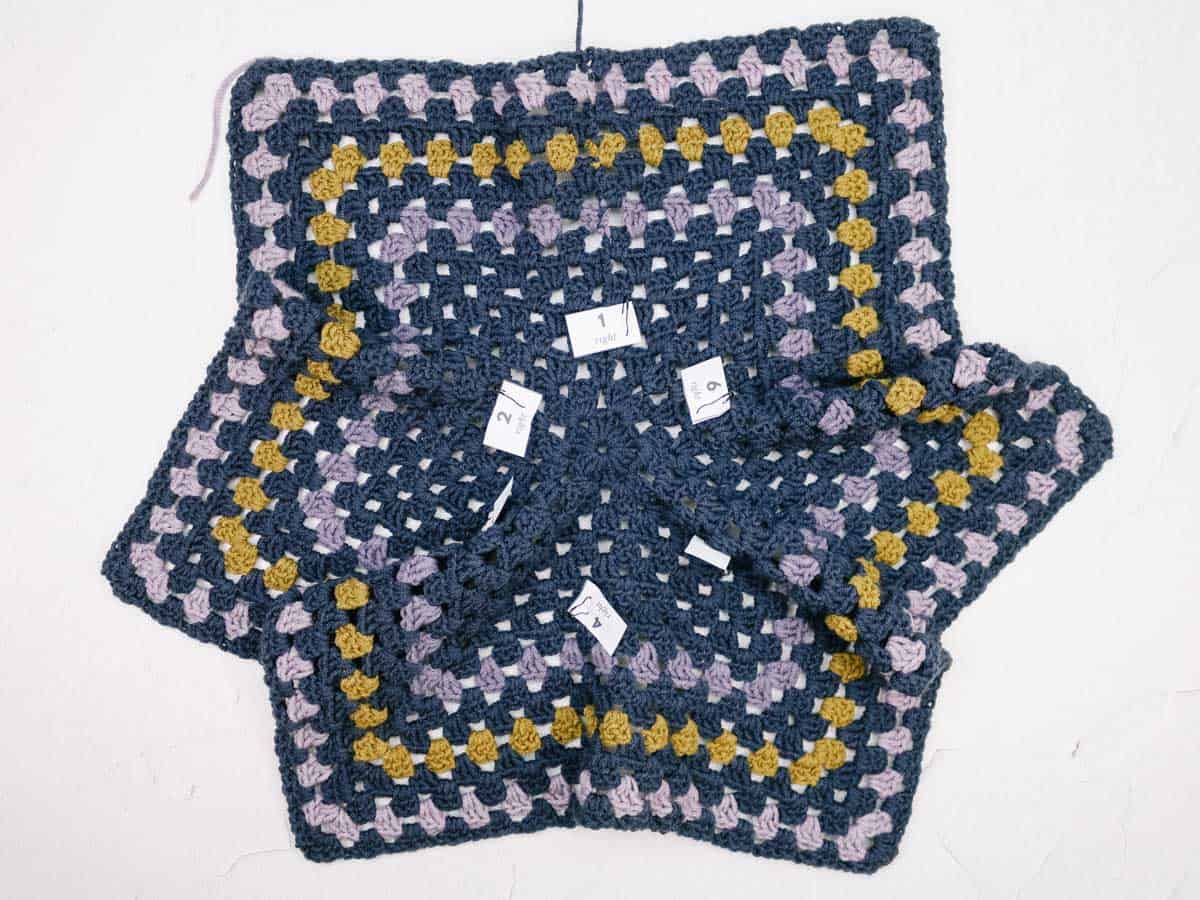 An in-progress crochet hexagon with labels laid flat.