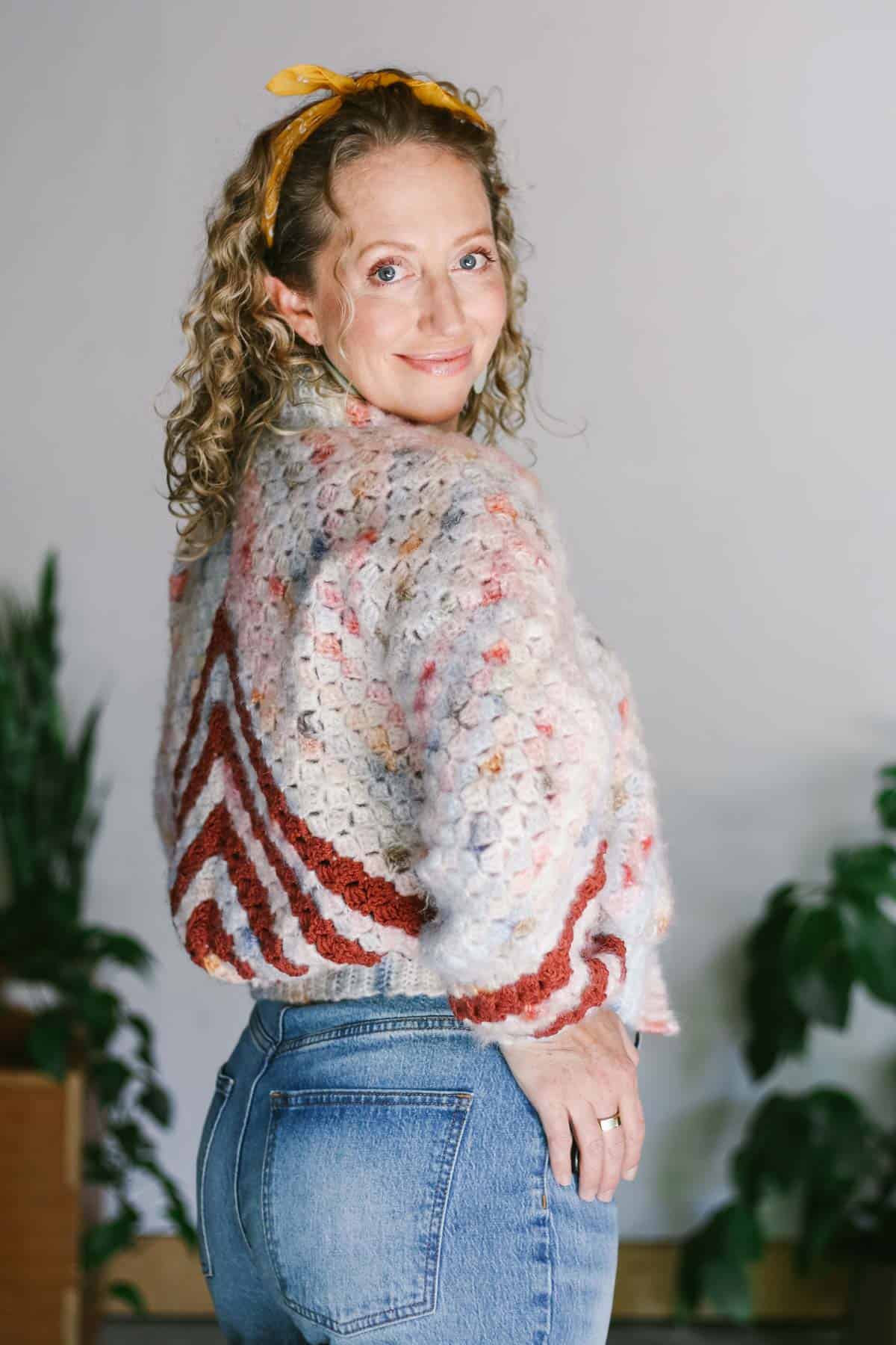 An easy corner to corner crochet cardigan worn by a blonde woman smiling at the camera.