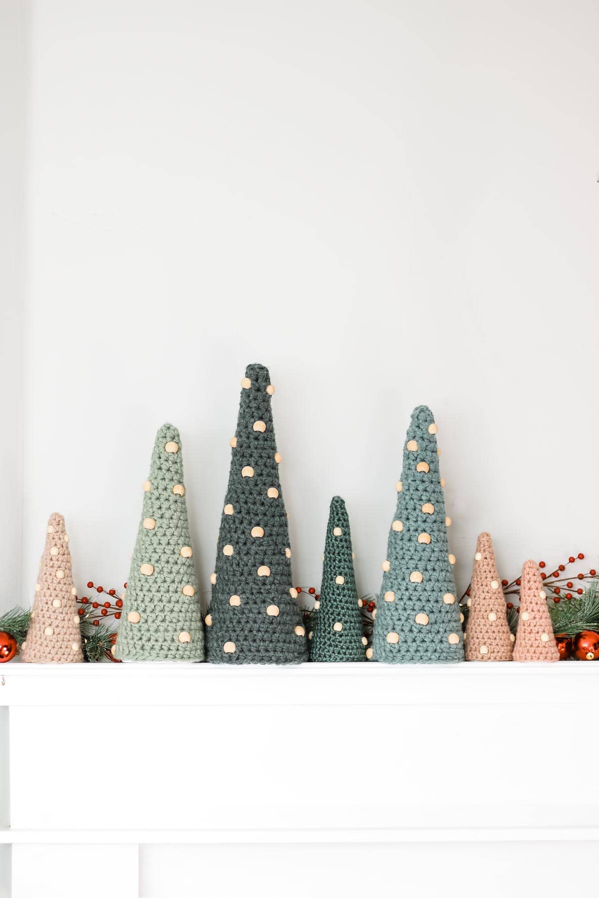 Seven crochet Christmas trees in small, medium and large sizes placed on top of a table.