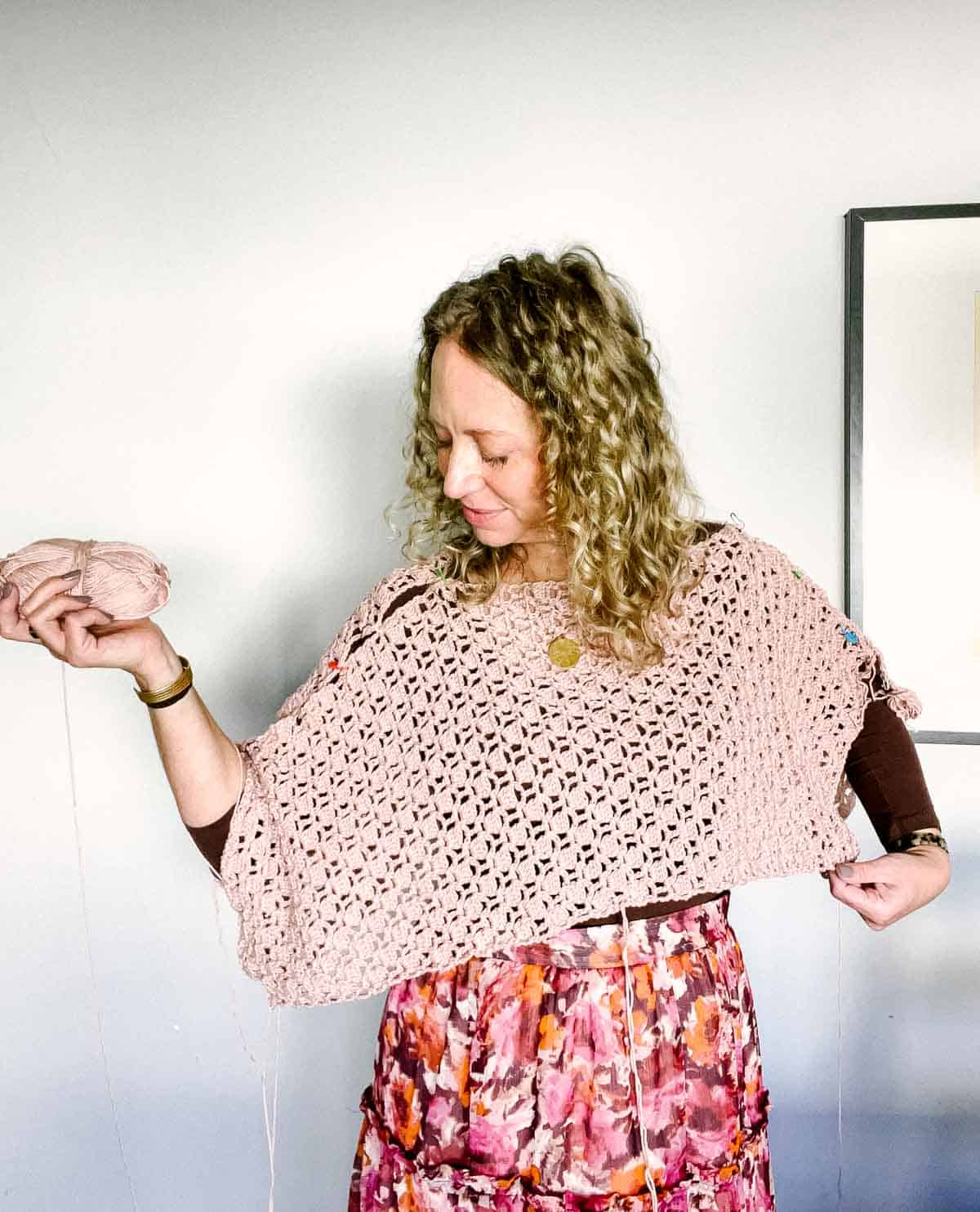 A lacy crochet sweater being tried on by a woman before seaming together.