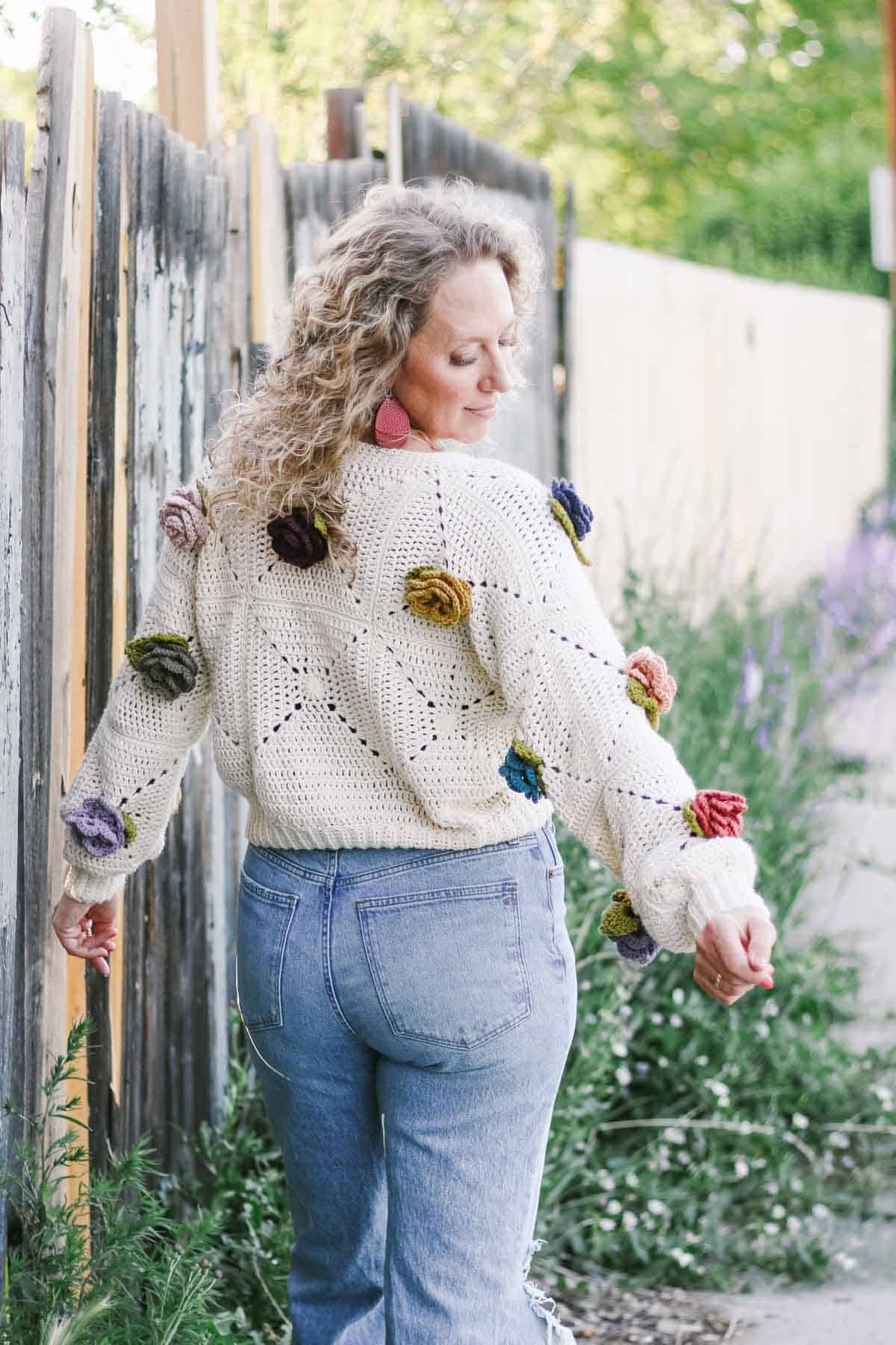 Crochet rosebud sweater modeled on a woman with back to camera.