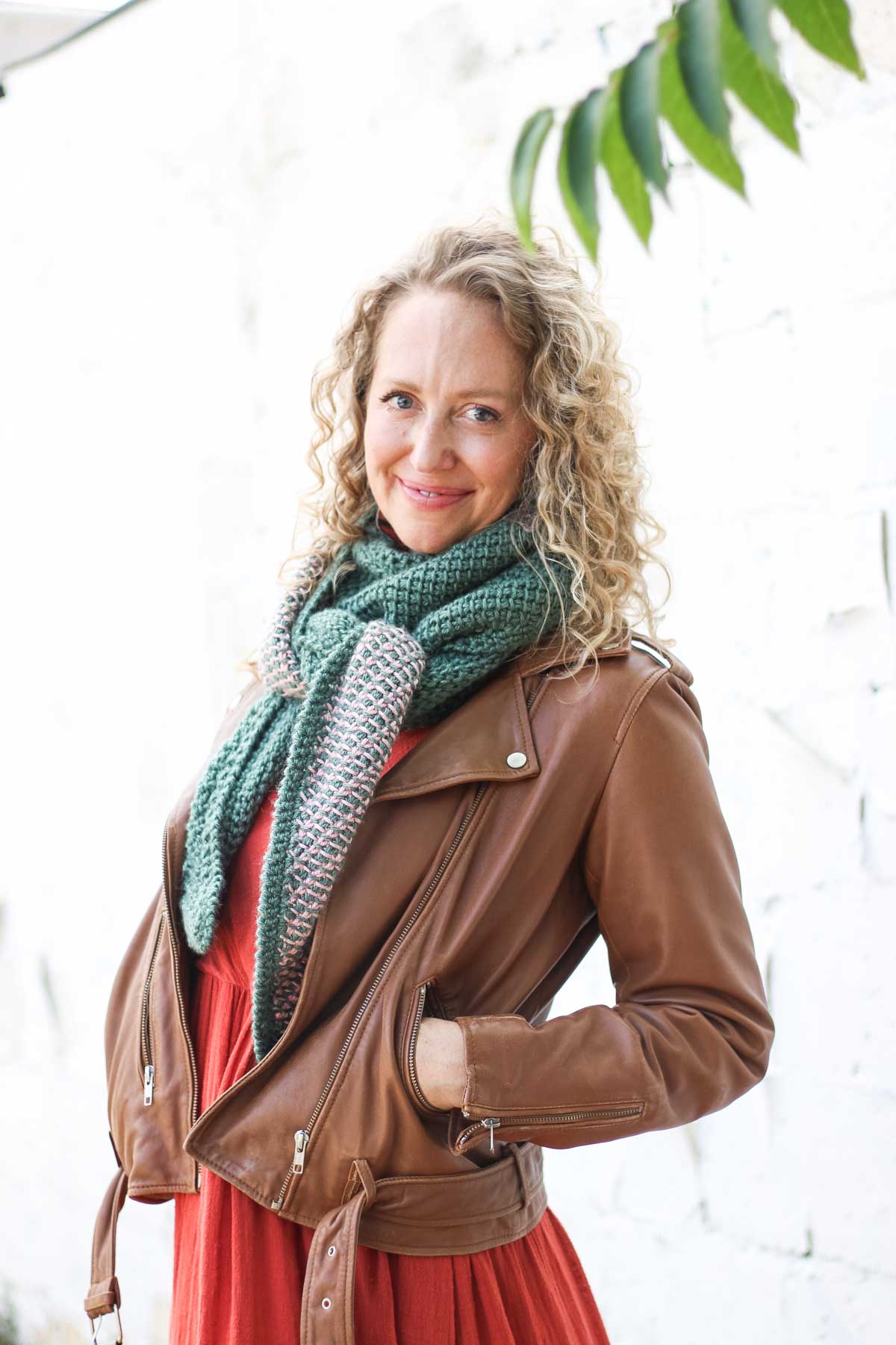 Smiling woman holding a striped Tunisian crochet boomerang shawl.
