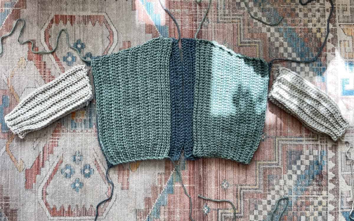 Crochet cardigan front, back and sleeve panels preparing for seaming.