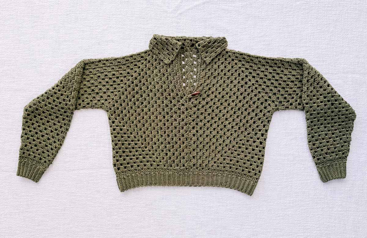 Finished cropped hexagon crochet sweater laying flat on a white background.
