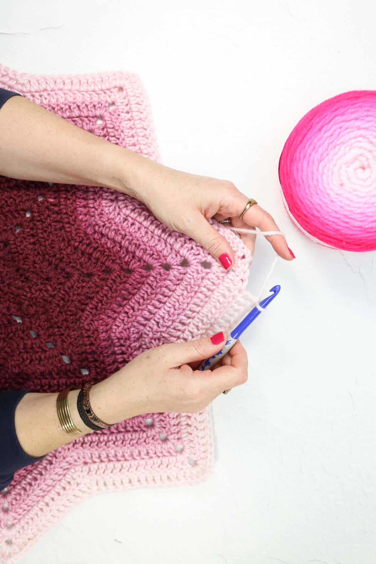 Hands crocheting a ripple star with Lion Brand Mandala Gradient yarn.
