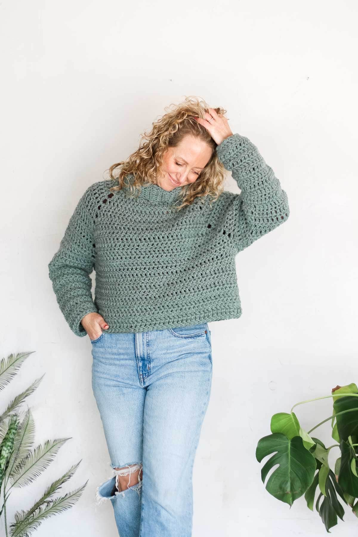 Woman wearing a chunky crochet raglan-style sweater with a turtleneck.