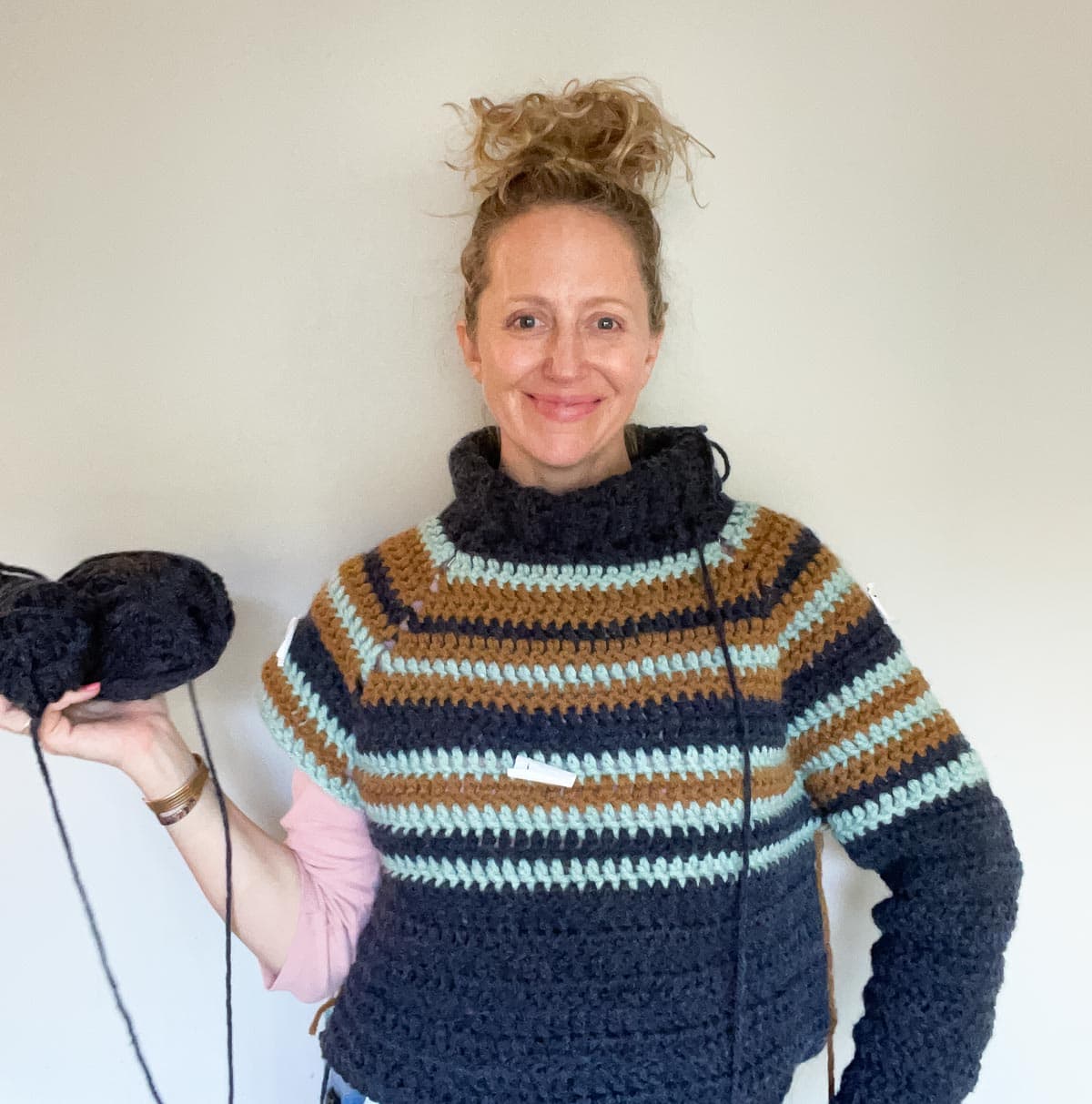 Jess Coppom trying on an in-progress crochet raglan sweater.