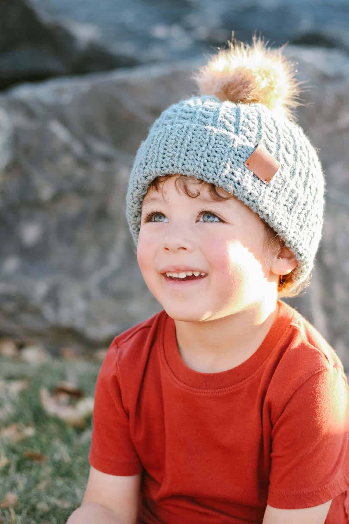 A blue textured crochet hat on a young child.