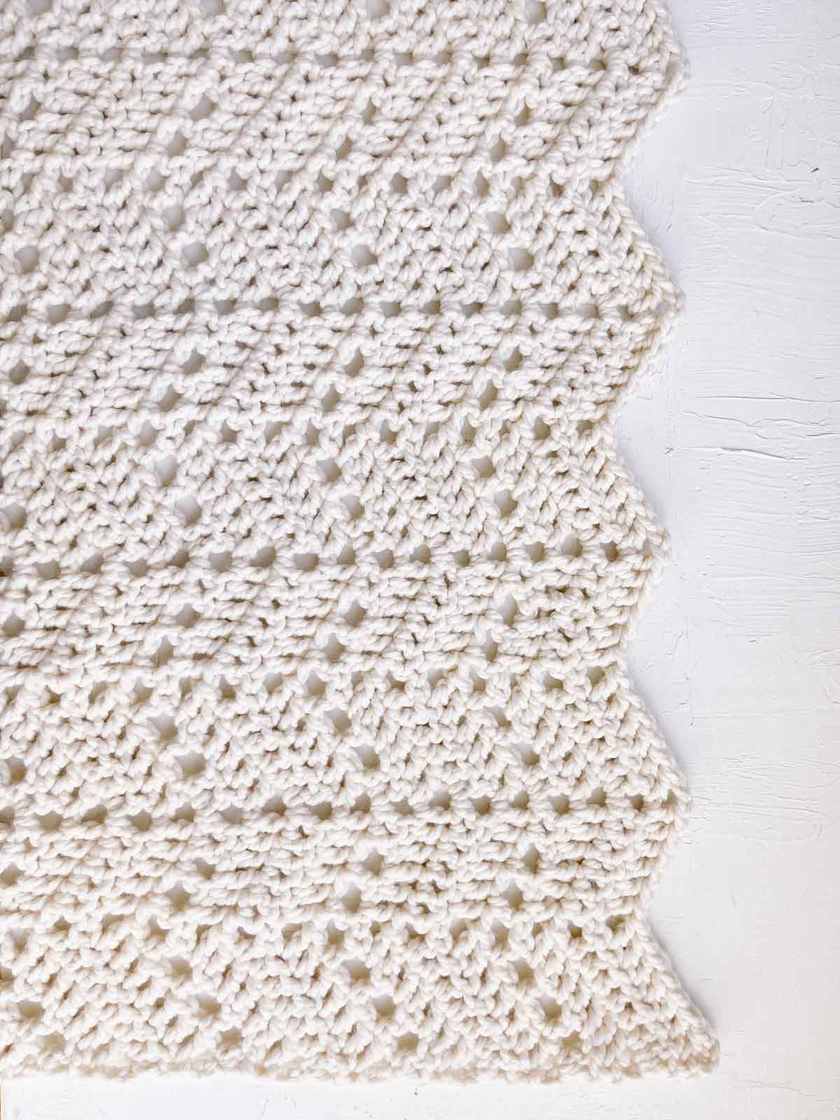 An ivory crochet eyelet ripple blanket made with Wool-Ease Thick & Quick yarn.