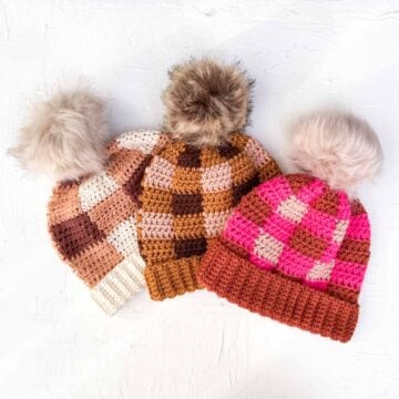 Three crochet plaid hats in various modern colors laying on a white background.