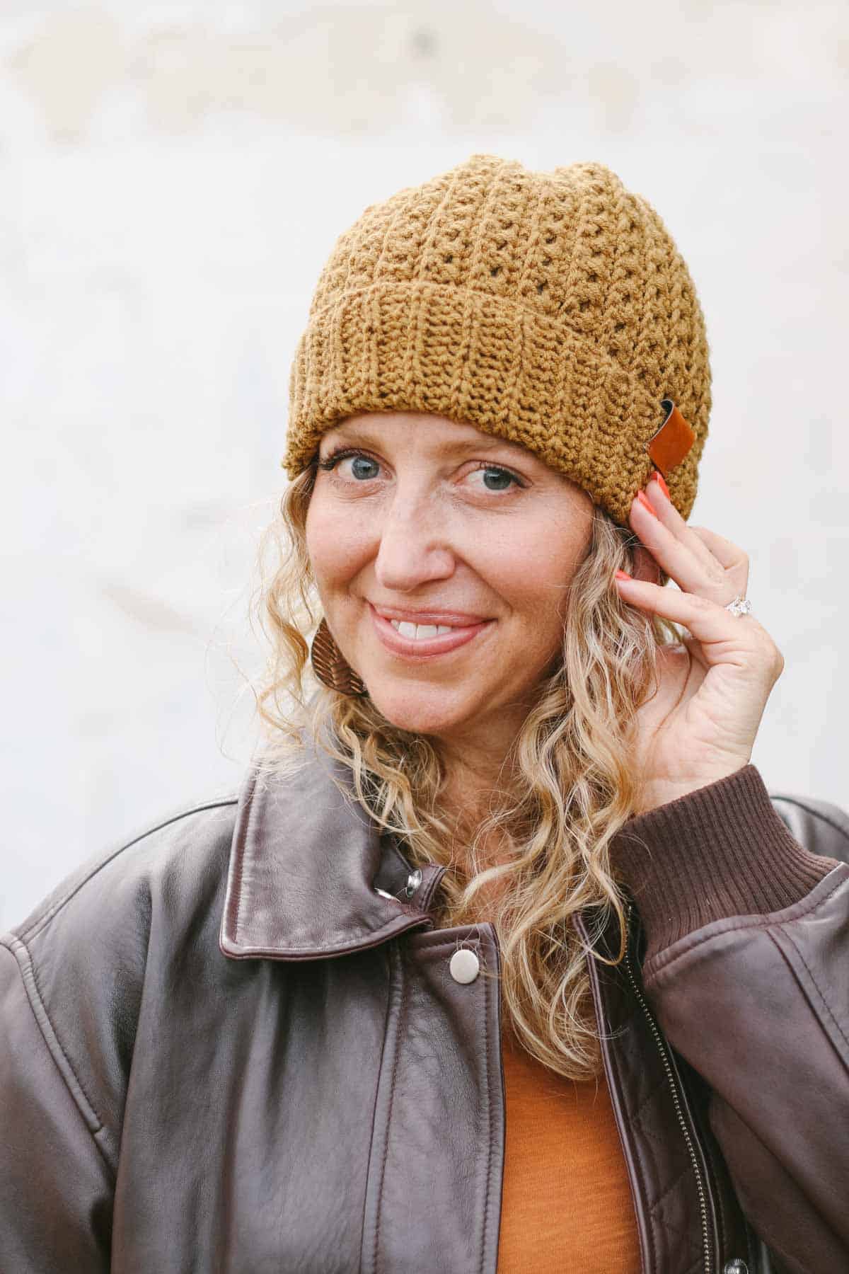Mustard-colored crochet beanie with a folded brim, modeled by Jess Coppom.