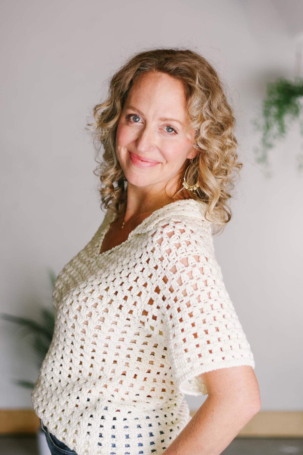 Side view of a short sleeved crochet shirt on a blonde woman.
