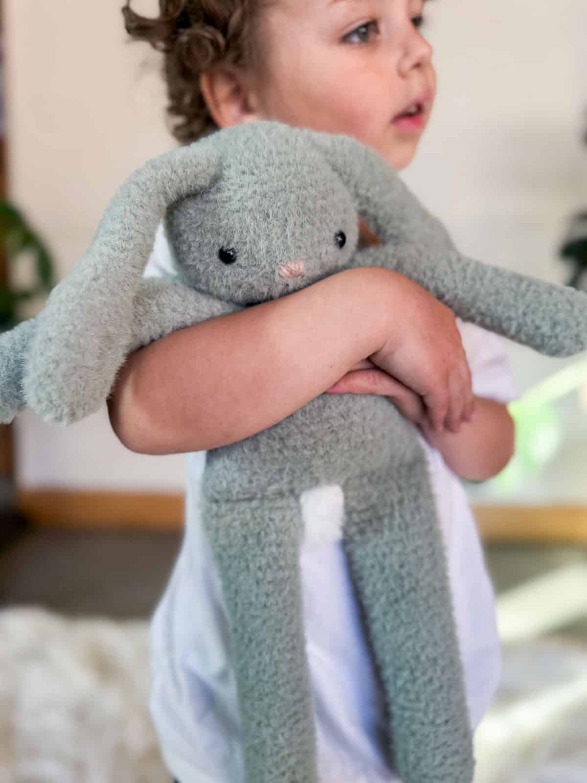 A classic crochet bunny stuffie held by a young child.