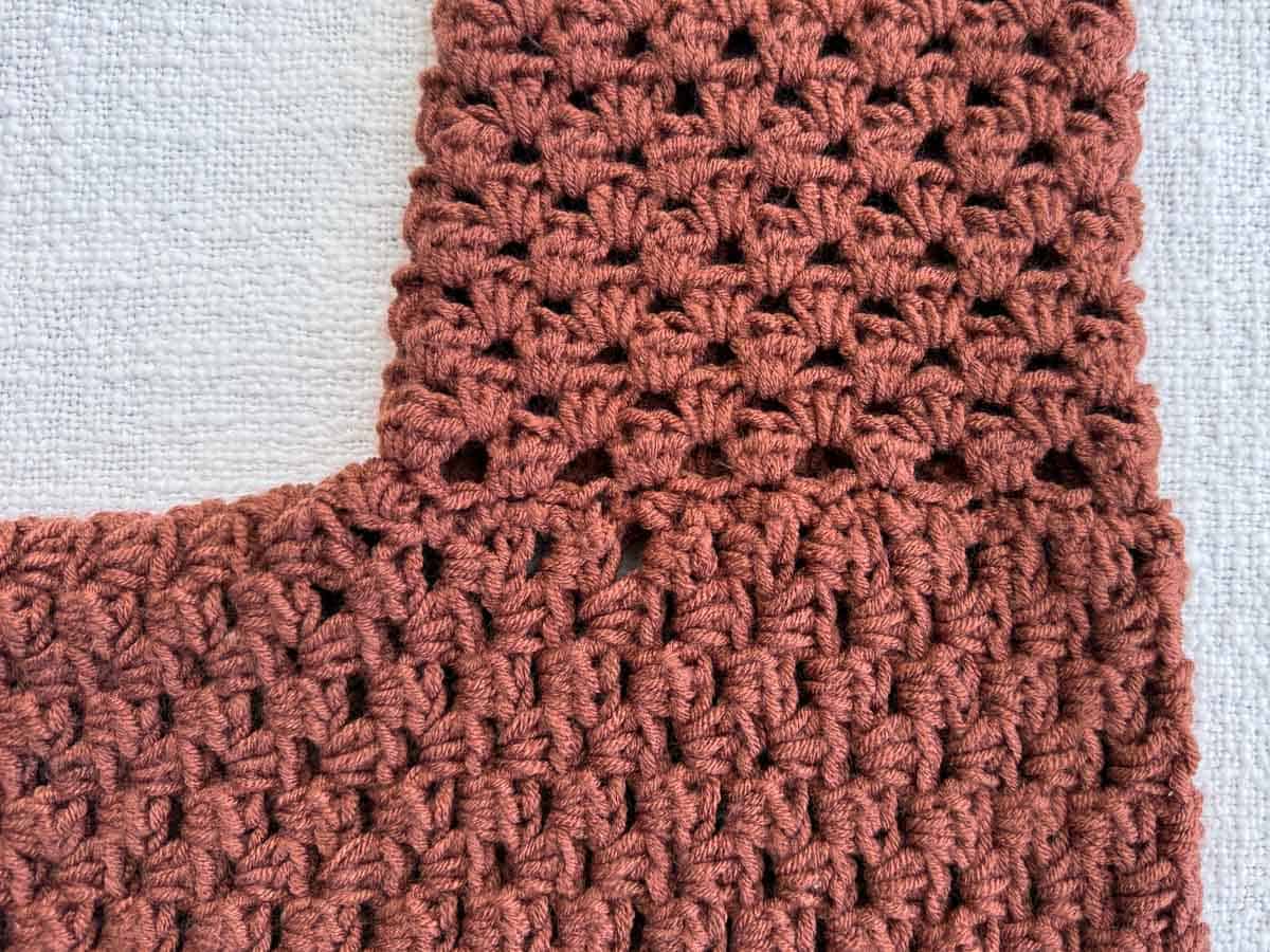 Close-up of the armhole shaping and half double crochet stitch pattern on the cardigan body panel.