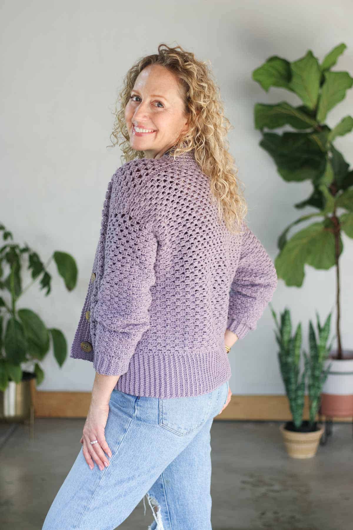 Side view of a half double crochet cardigan in dusty lavender Lion Brand Color Theory yarn, showing the sleeve shaping and stitch texture.