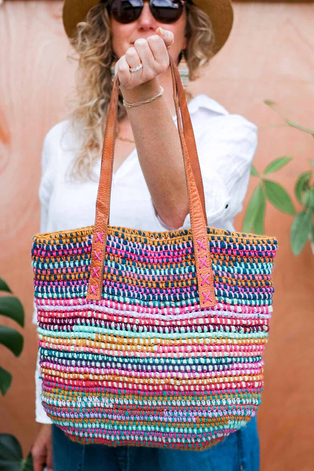 Crocheted scrap yarn bag with zero-waste handles, held by a woman.
