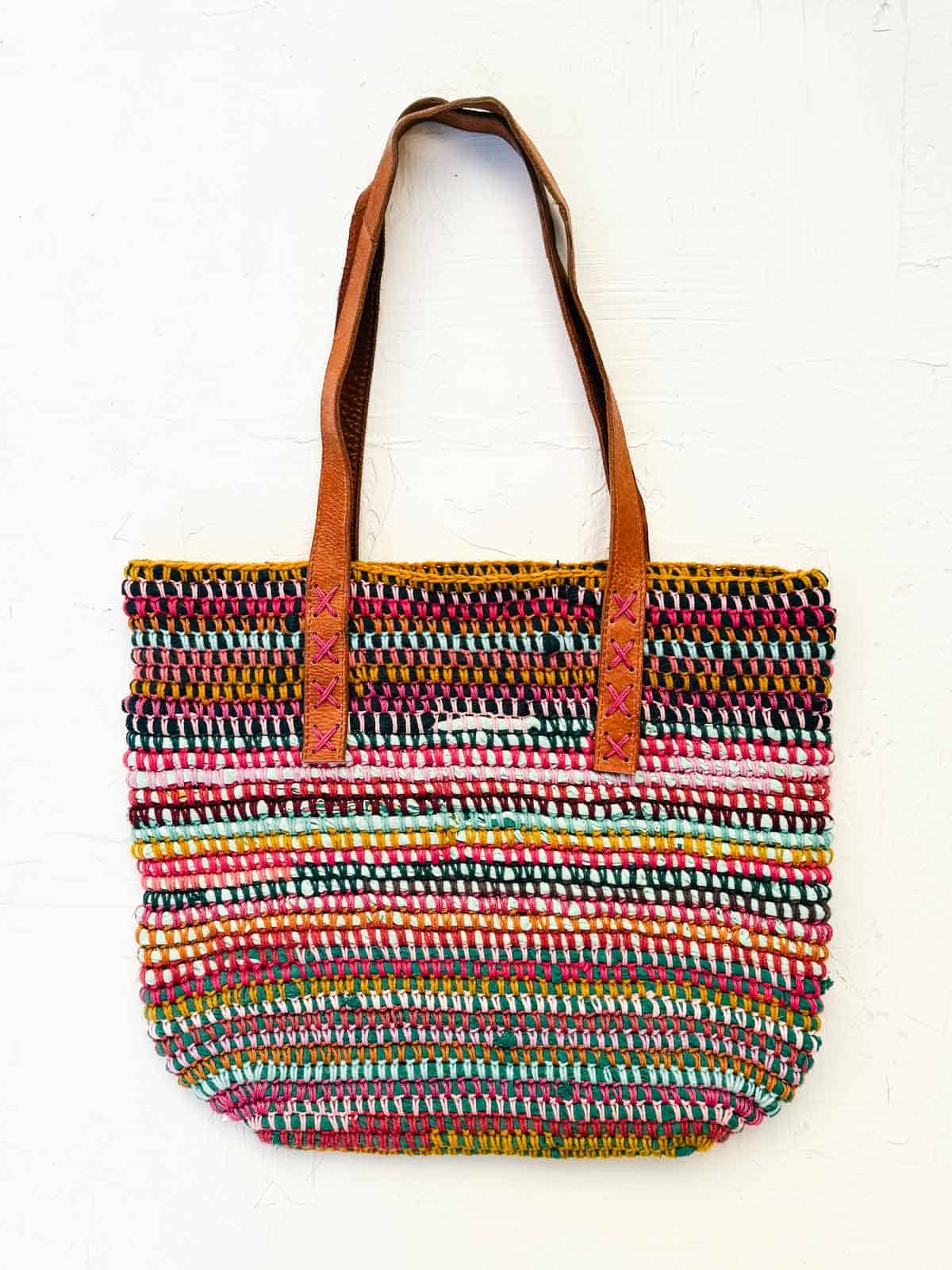 Multicolor crochet scrap yarn bag make with upcycled clothing and repurposed leather handles.