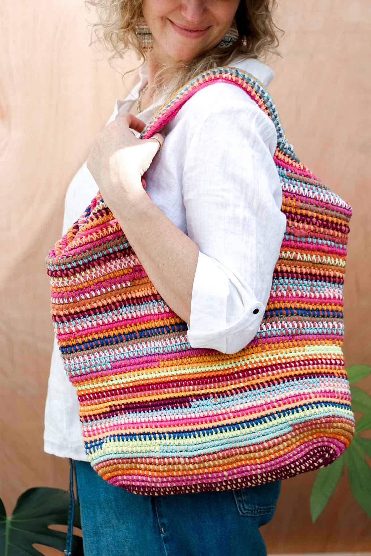 Crocheted scrap yarn bag with zero-waste handles, held by a woman.