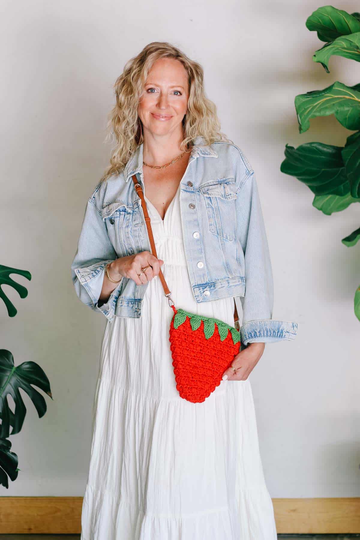 Small crochet strawberry pocketbook with puff stitches and a leather strap.